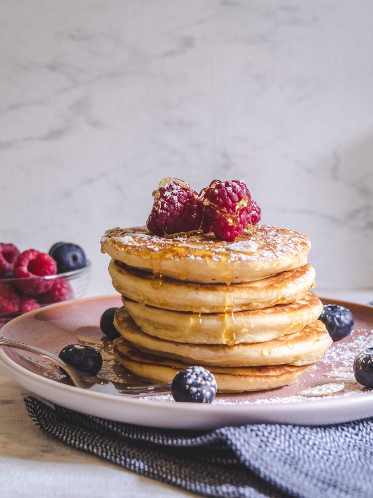 A Stack of Pancakes with Berries and Powdered Sugar